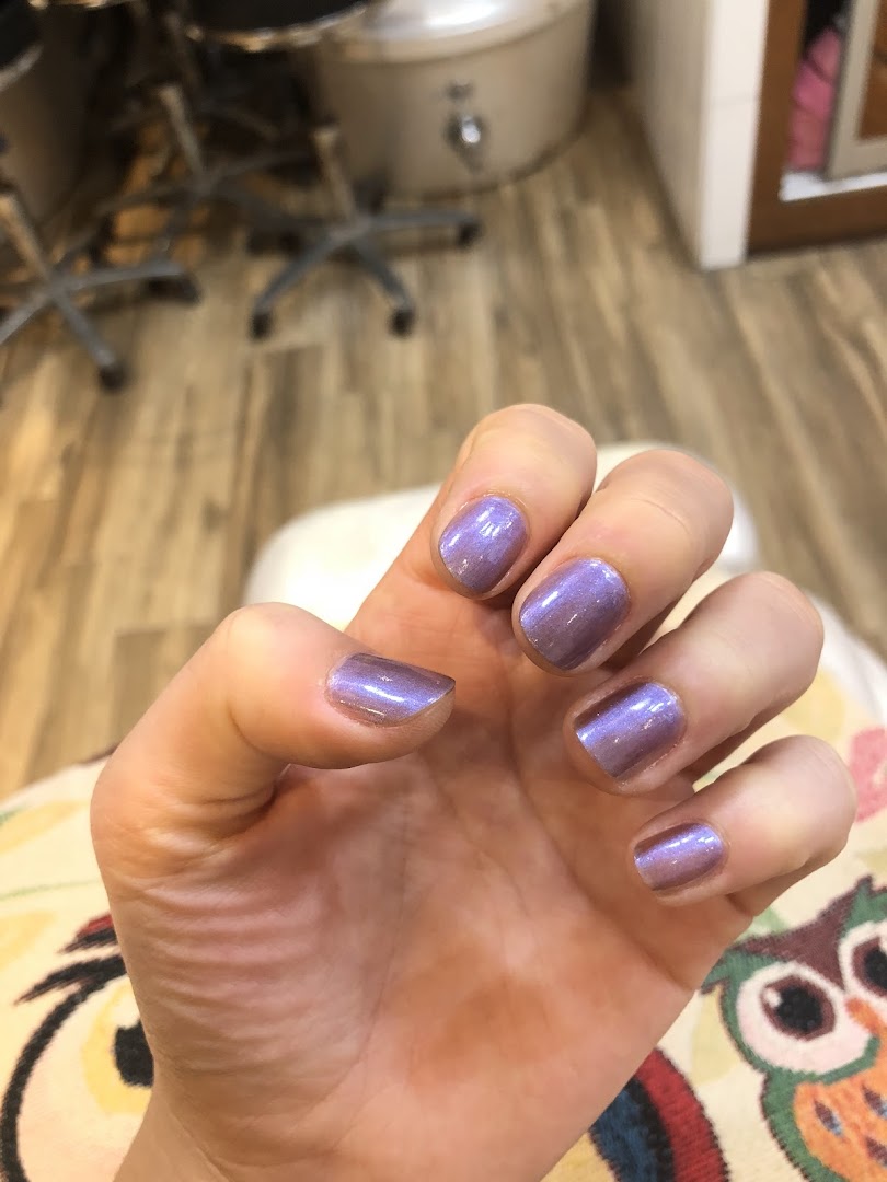 A hand showcasing freshly painted iridescent purple nails, highlighting a service from Pixie Nail Spa.