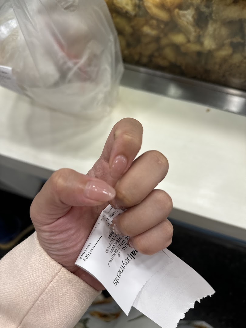 A hand with freshly manicured nails holds a receipt, showcasing the spa's service quality.