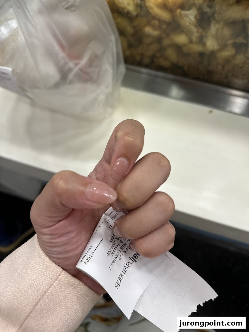 A hand with freshly manicured nails holds a receipt, showcasing the spa's service quality.