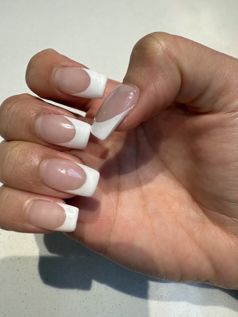 A hand showcasing freshly done French tip nails with a modern, square-shaped design.
