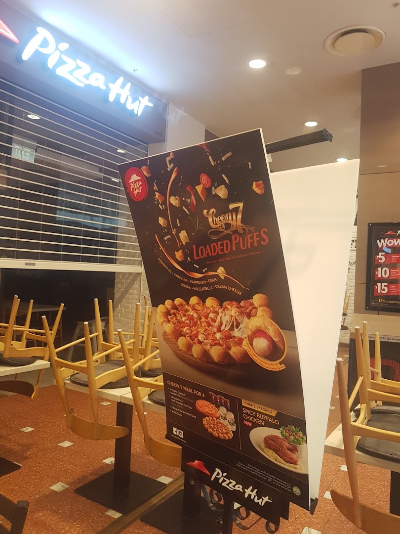An interior view of Pizza Hut featuring a promotional stand for Cheesy Loaded Puffs and Spicy Buffalo Chicken.