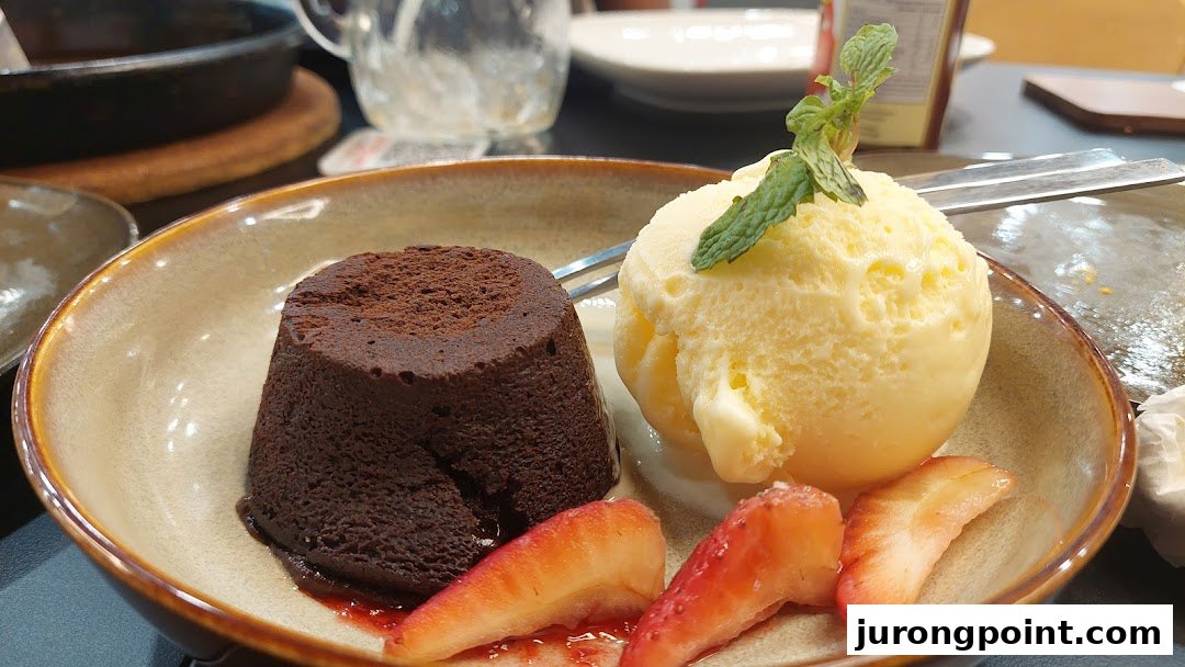 A decadent chocolate lava cake served with vanilla ice cream and fresh strawberries.
