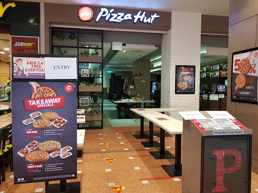 The entrance of a Pizza Hut restaurant with takeaway specials and promotional signage.