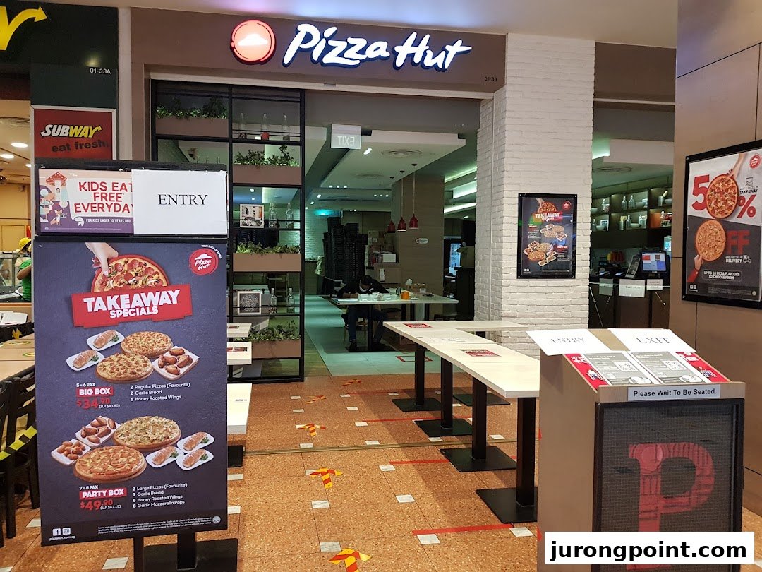 The entrance of a Pizza Hut restaurant with takeaway specials and promotional signage.