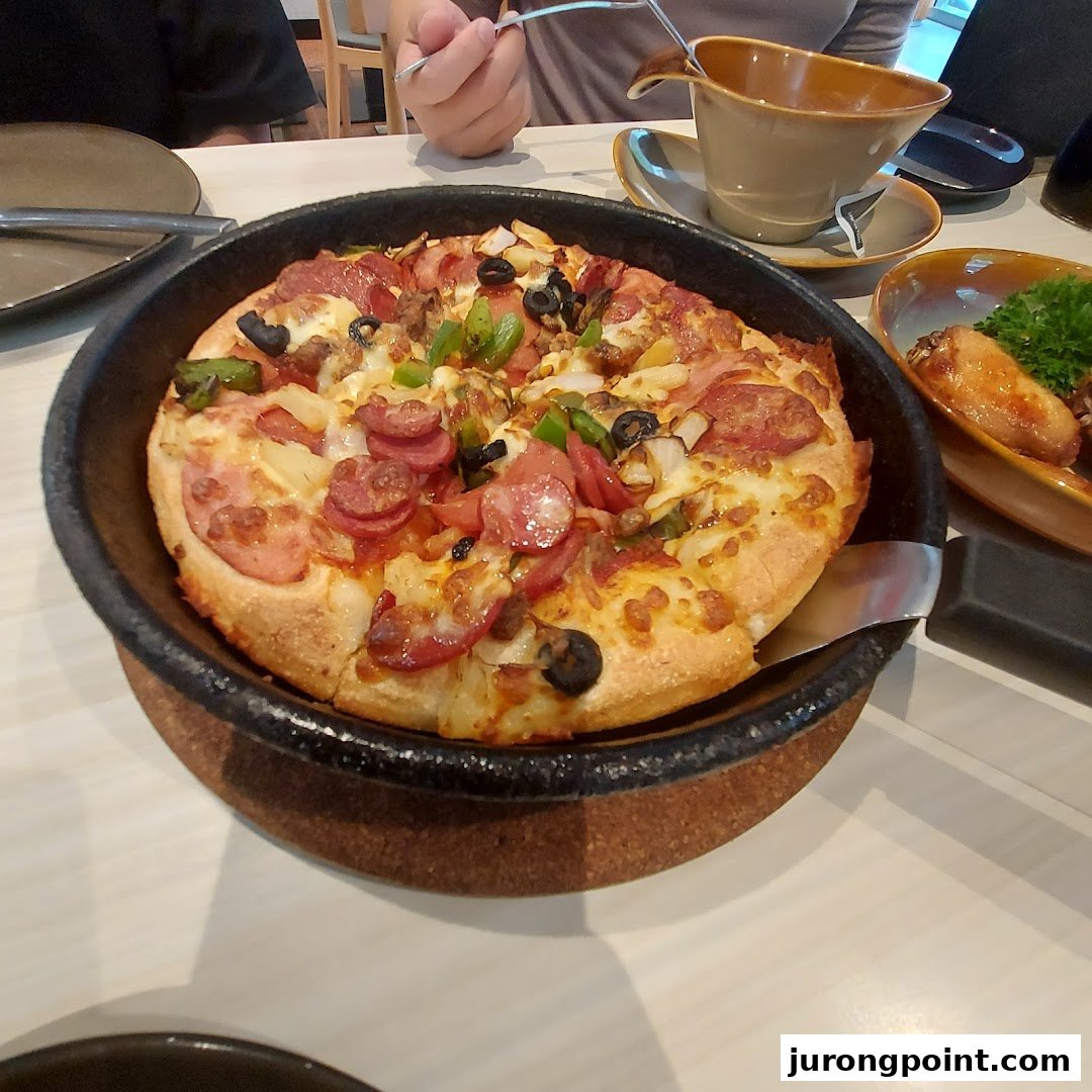 A delicious pan pizza with various toppings served in a cast-iron pan at Pizza Hut.