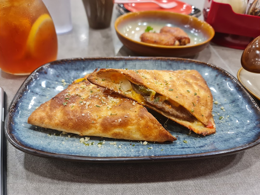 A golden-brown folded pizza or calzone, garnished with herbs, served with iced tea.
