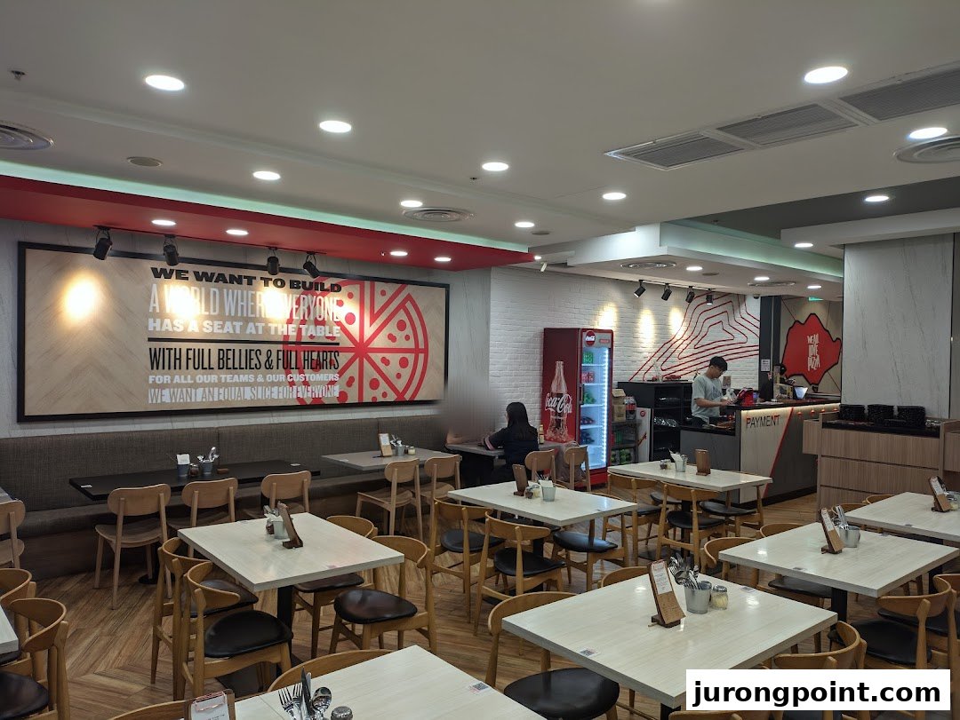 A bright and inviting interior of Pizza Hut with dining tables and a service counter.