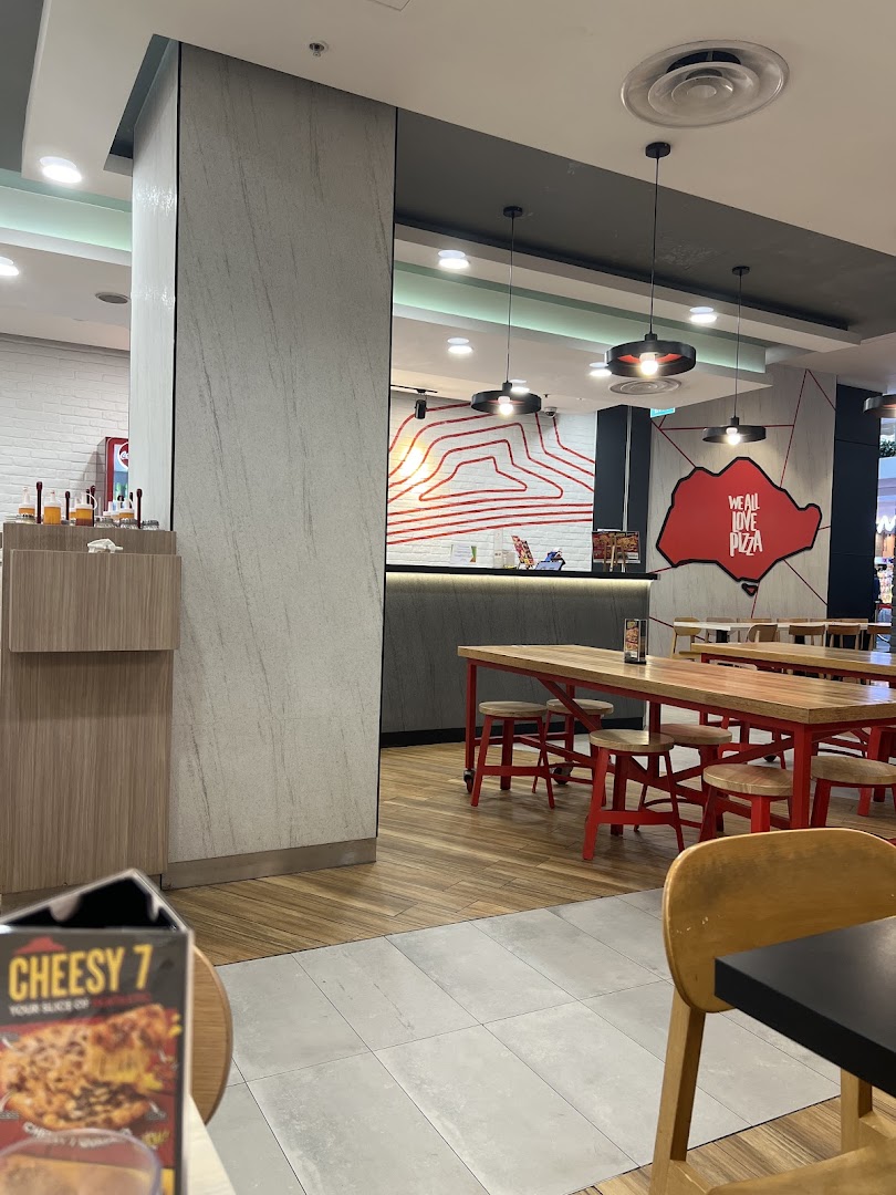 Interior view of Pizza Hut with dining tables, a service counter, and brand decor.