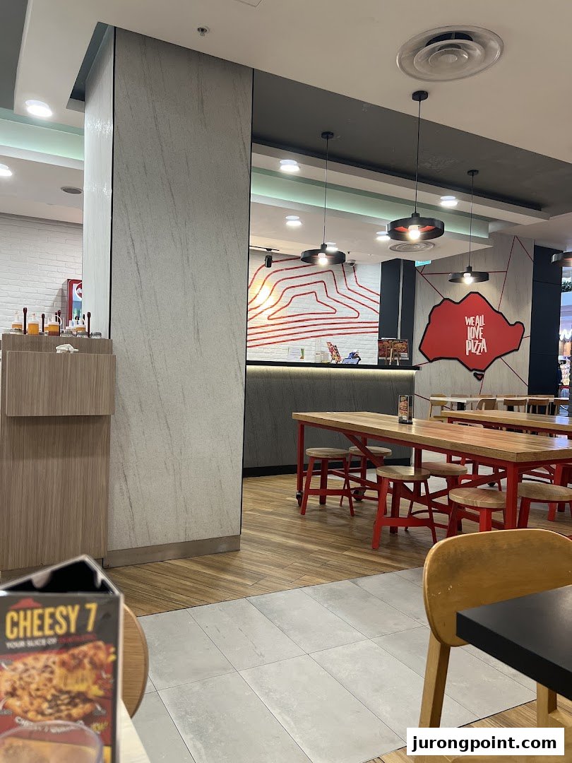 Interior view of Pizza Hut with dining tables, a service counter, and brand decor.
