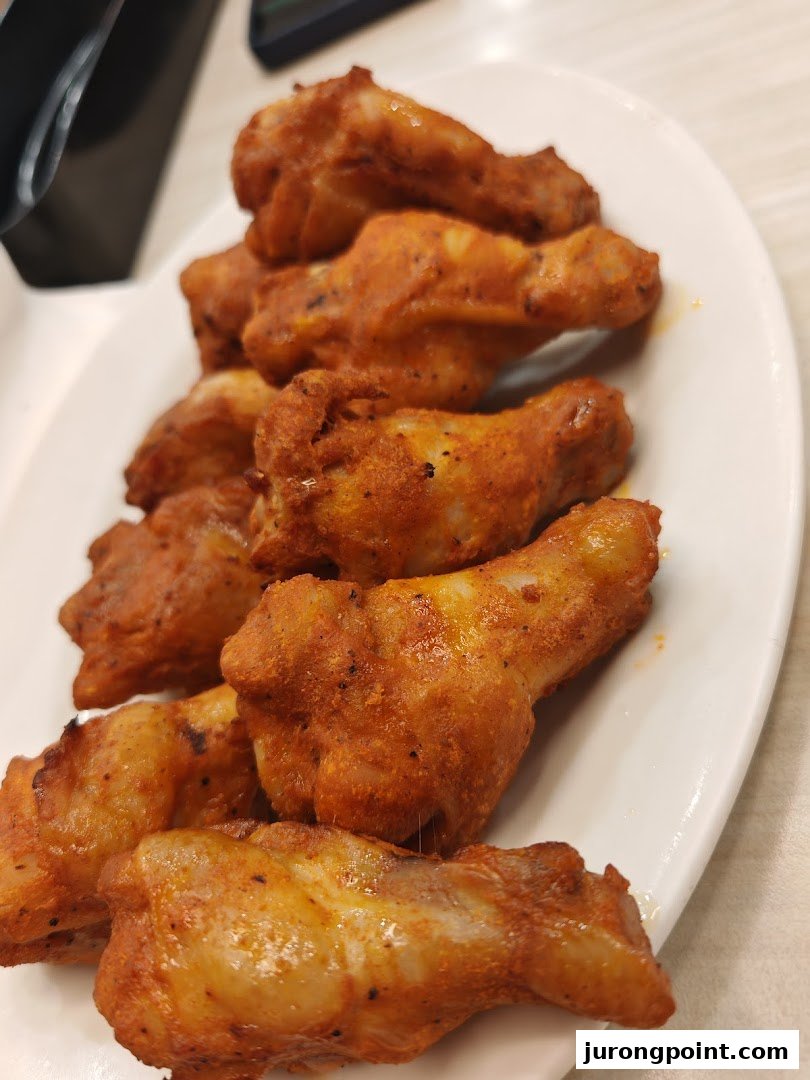 A close-up of a plate filled with golden-brown, seasoned chicken wings.