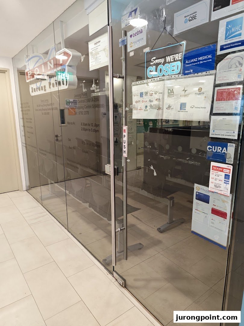 The glass entrance of Point Medical Group at Jurong Point, displaying operating hours and partner affiliations.