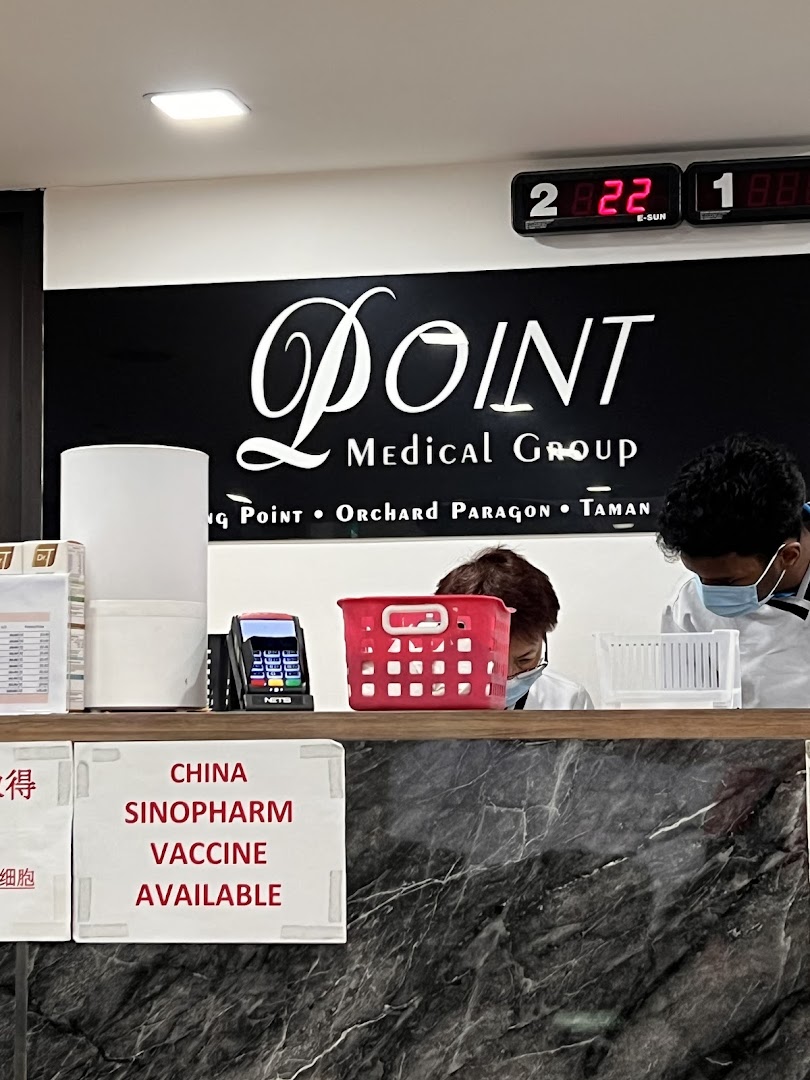 Reception counter of Point Medical Group, showing staff and a sign for Sinopharm vaccine availability.