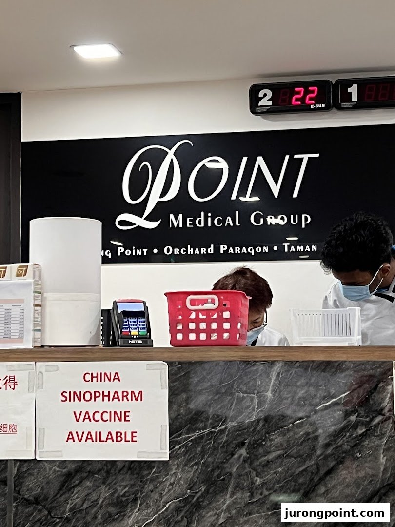 Reception counter of Point Medical Group, showing staff and a sign for Sinopharm vaccine availability.