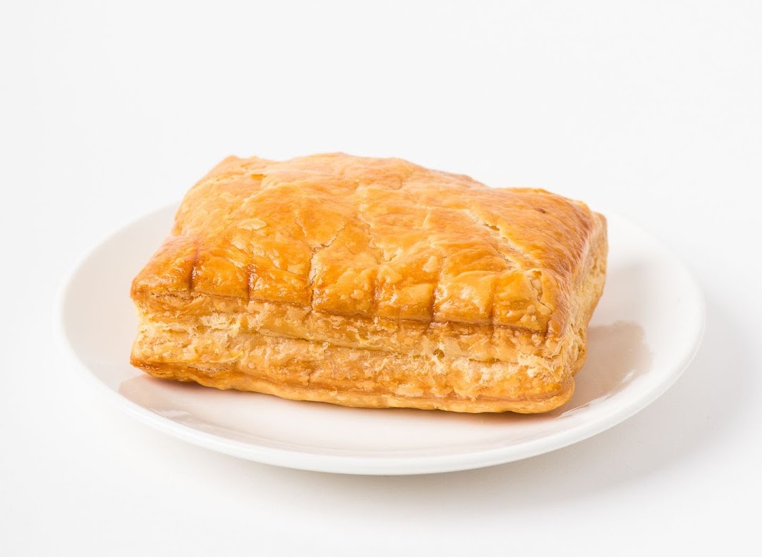 A golden-brown puff pastry, possibly a curry puff, presented on a white plate.
