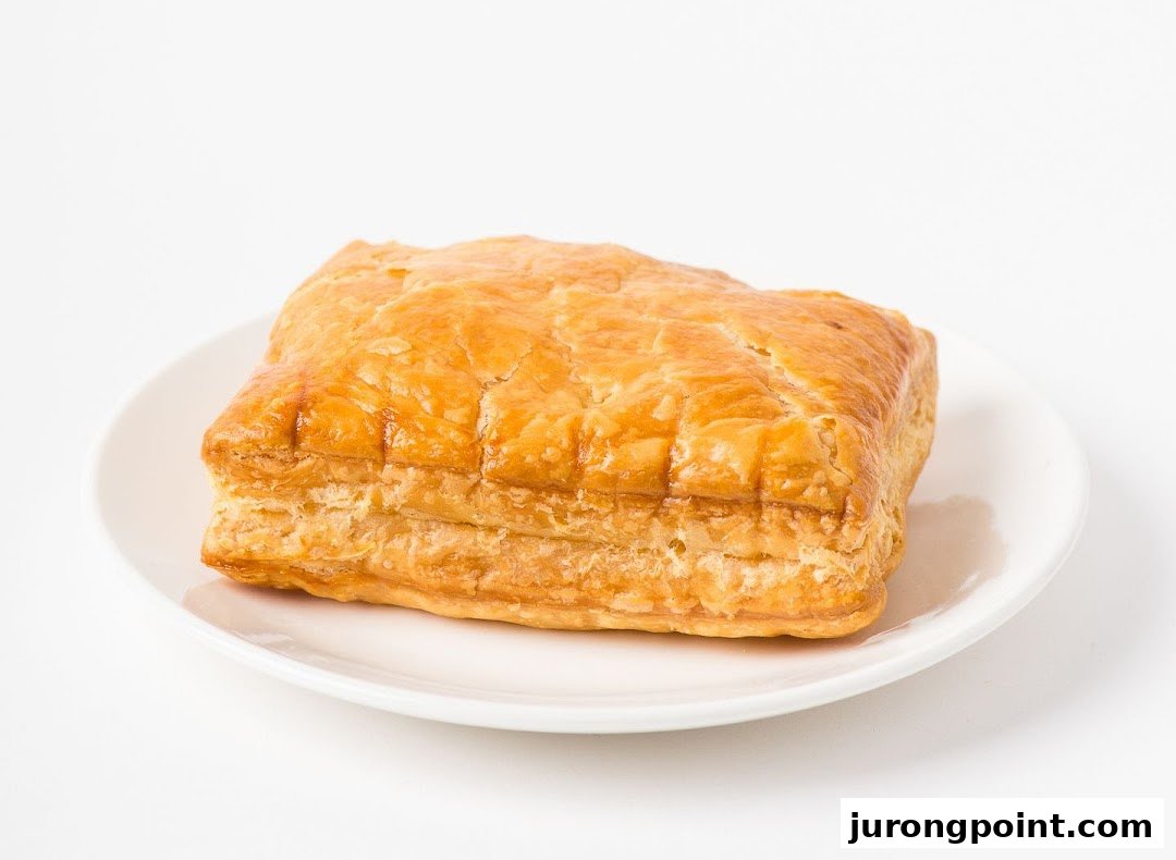 A golden-brown puff pastry, possibly a curry puff, presented on a white plate.
