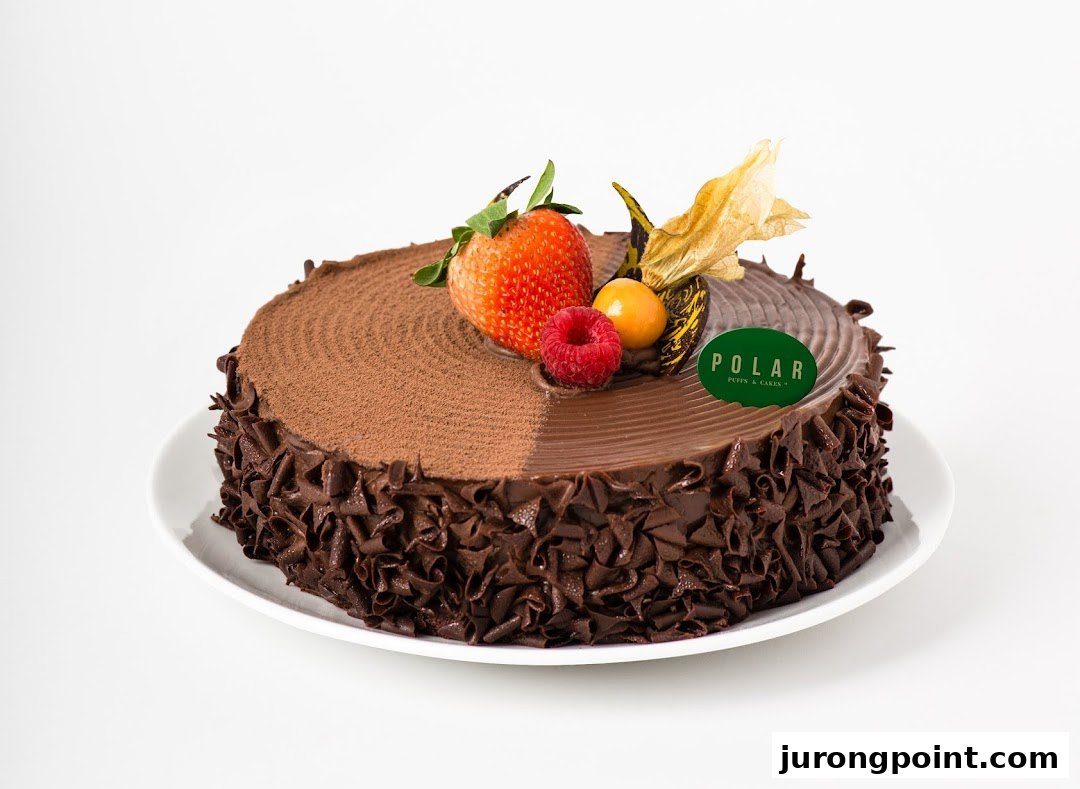 A decadent chocolate cake from Polar Puffs & Cakes, adorned with fresh berries and a brand tag.