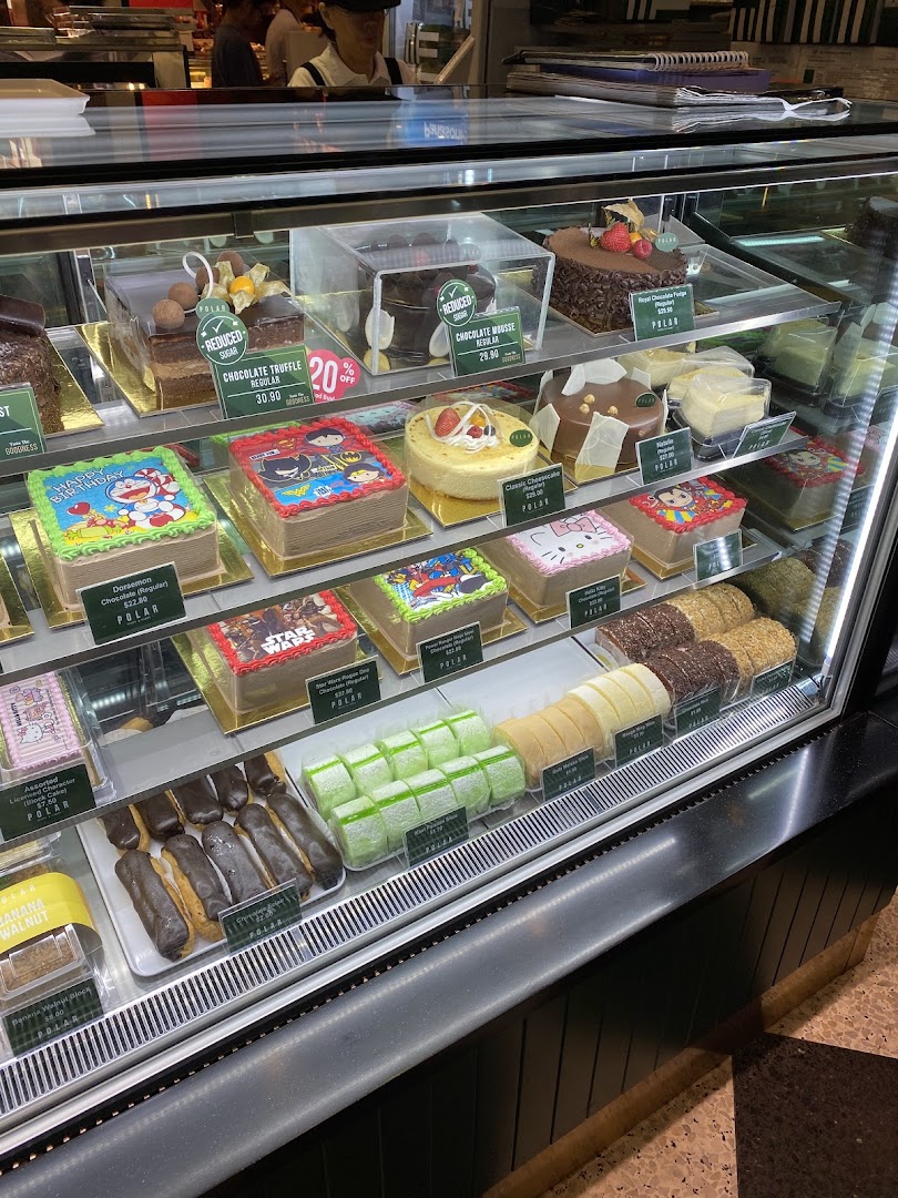 A vibrant display case showcasing a variety of delicious cakes, pastries, and character-themed treats at Polar Puffs & Cakes.