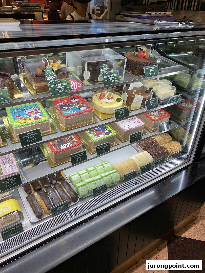 A vibrant display case showcasing a variety of delicious cakes, pastries, and character-themed treats at Polar Puffs & Cakes.