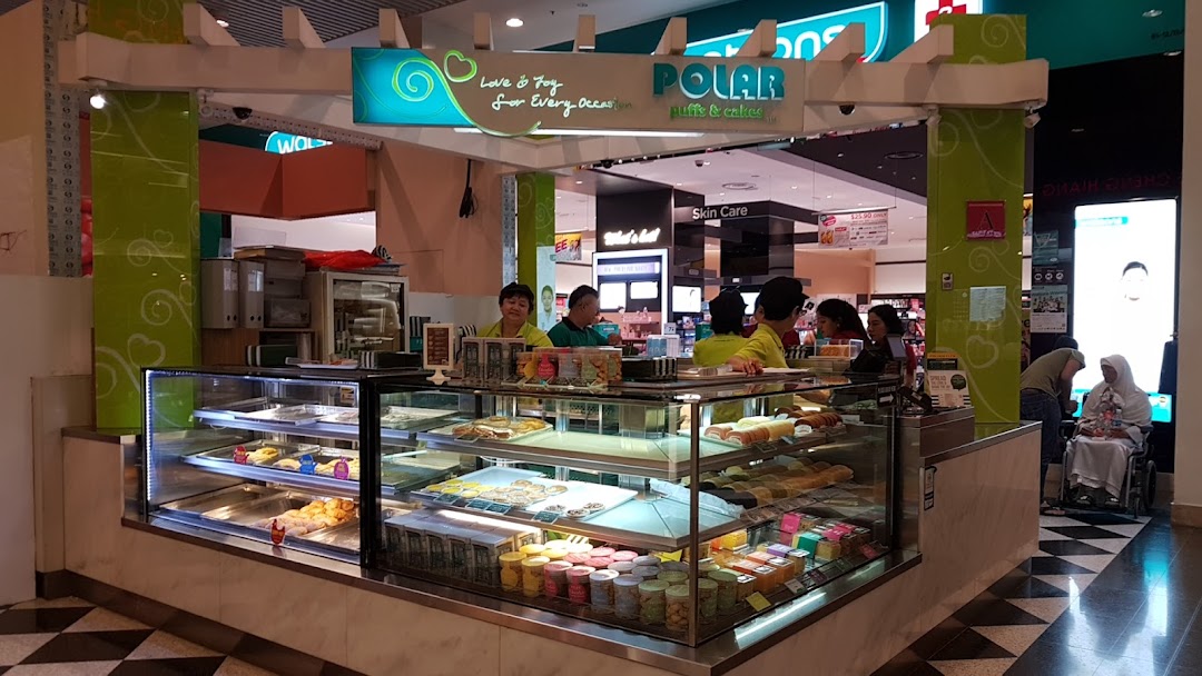 A bustling Polar Puffs & Cakes kiosk in a mall, showcasing a variety of pastries and cakes in display cases.