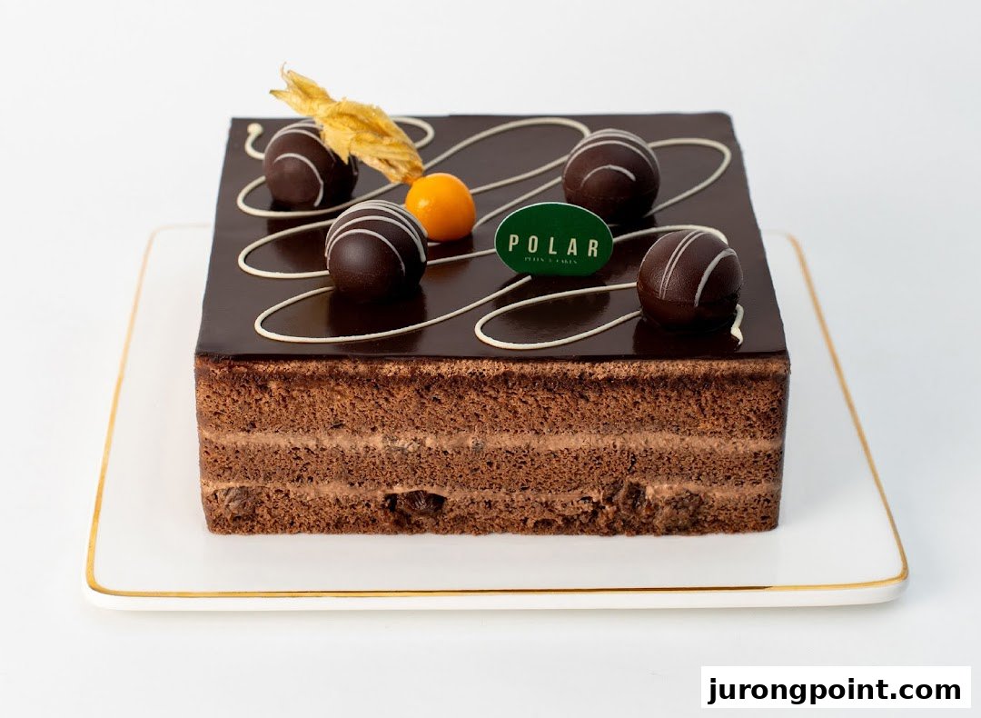 A decadent square chocolate cake with rich ganache, chocolate truffles, and fruit garnishes.