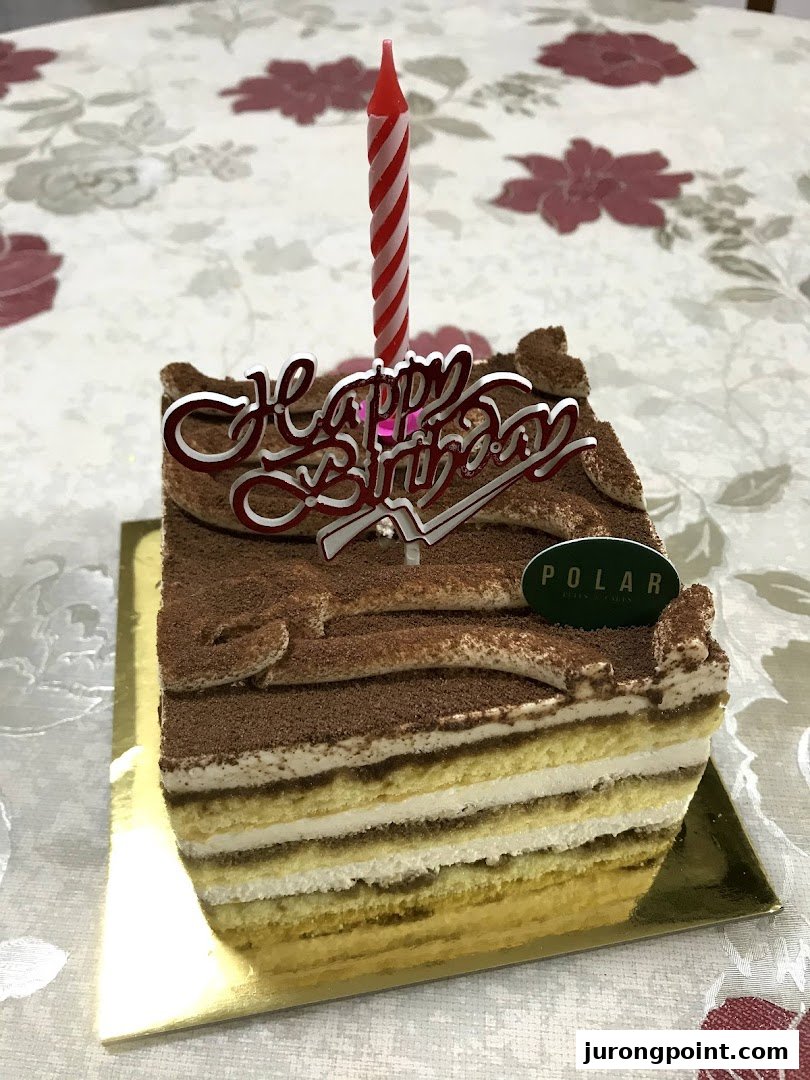 A delicious slice of tiramisu cake from Polar Puffs & Cakes with a birthday candle.
