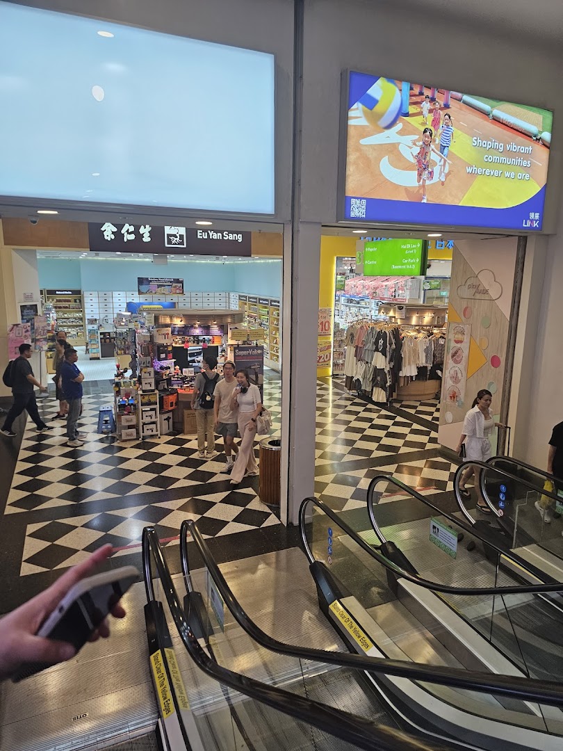 A mall interior showing the entrances of Eu Yan Sang and another retail shop, featuring a distinctive checkered floor and escalators.