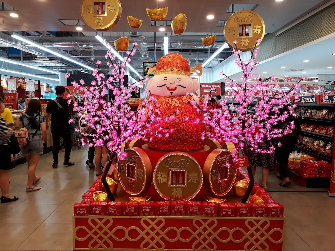 A festive display featuring a large character, pink cherry blossom trees, and Coca-Cola products inside a retail store.