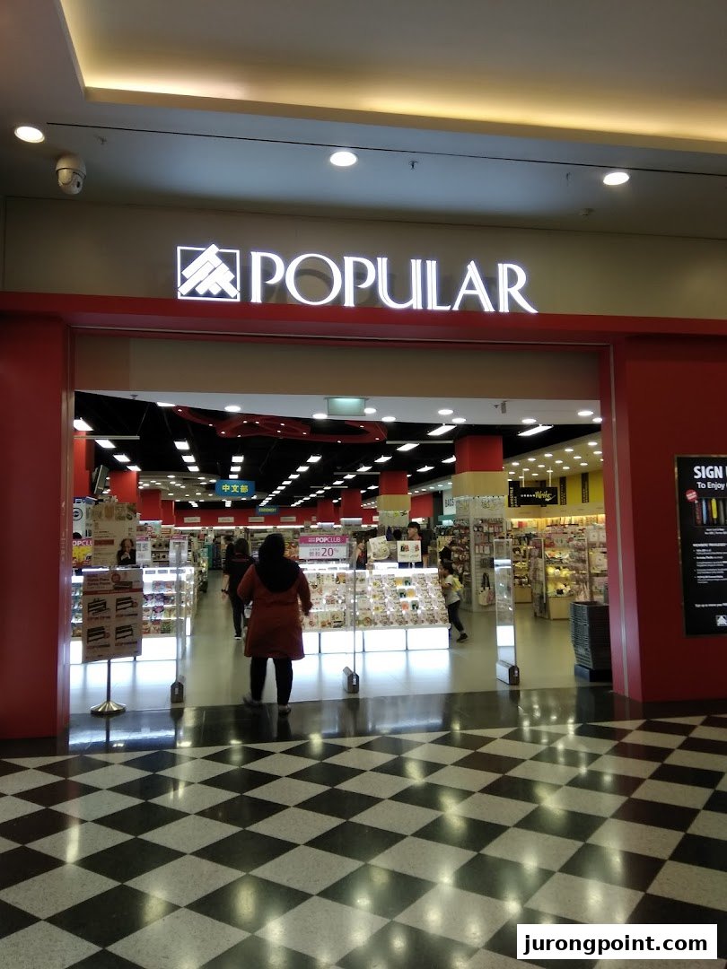 The brightly lit entrance of POPULAR Bookstore with a customer entering.