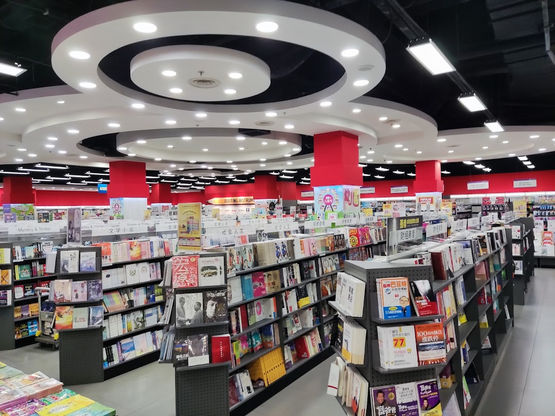 Interior view of a spacious bookstore with numerous shelves filled with books and bright lighting.
