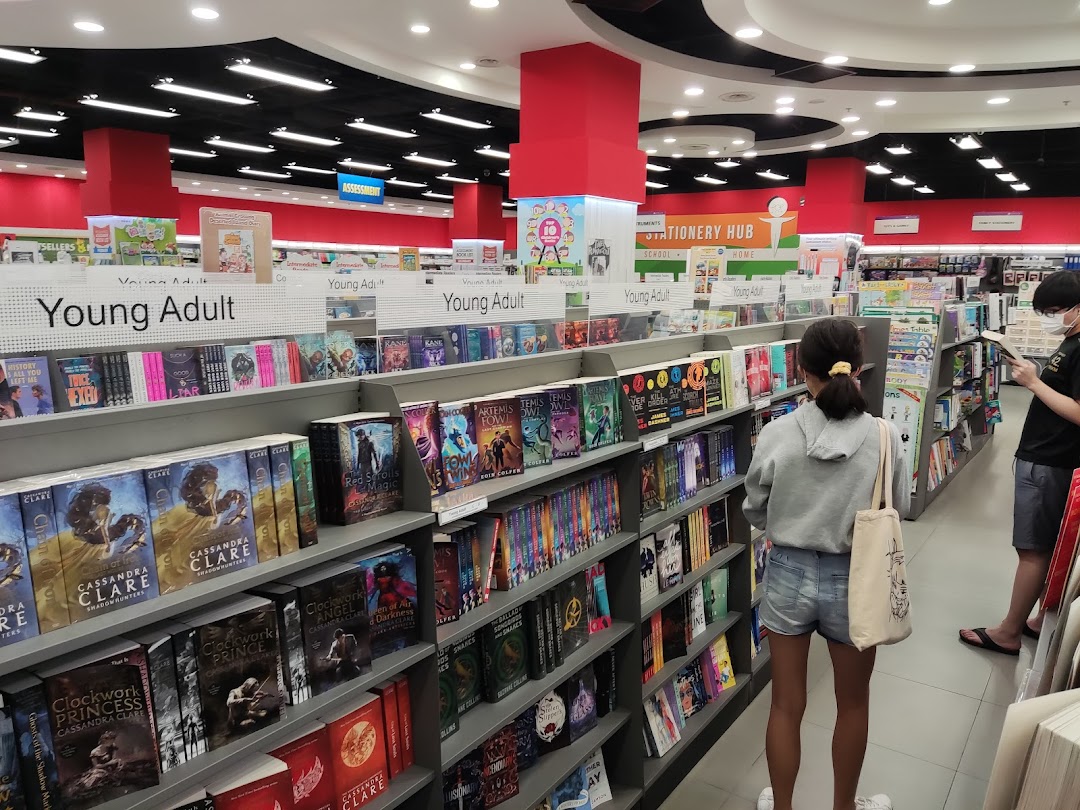 Customers browse books in the Young Adult section of a brightly lit bookstore.