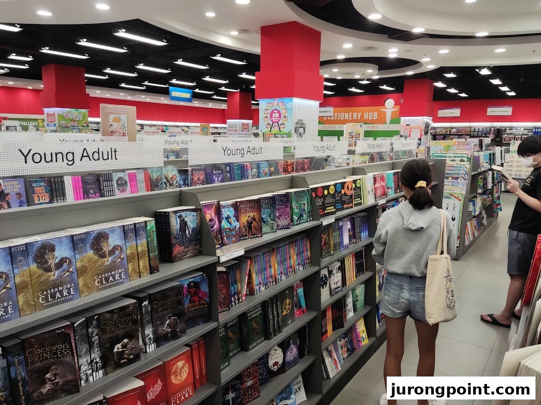 Customers browse books in the Young Adult section of a brightly lit bookstore.