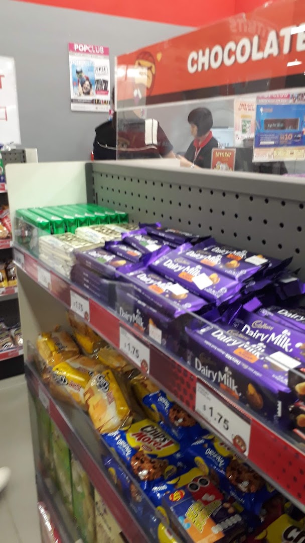A retail counter inside a bookstore displaying chocolates and snacks, with a staff member visible.