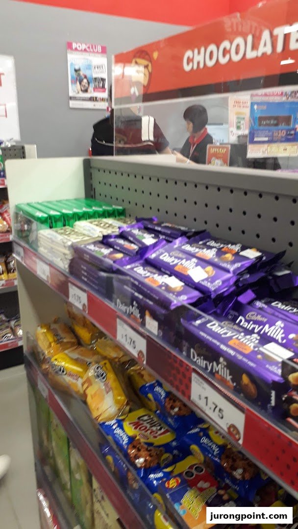 A retail counter inside a bookstore displaying chocolates and snacks, with a staff member visible.