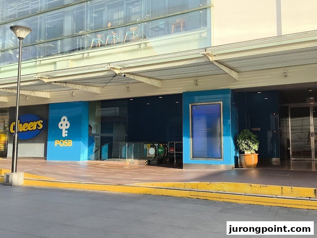 Exterior view of POSB Jurong Point Branch entrance, featuring an escalator and adjacent Cheers convenience store.