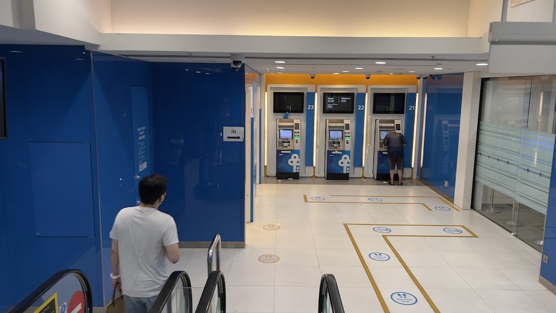 View of the POSB banking area with ATMs and a customer, accessible via escalator.
