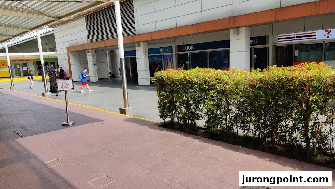 Exterior view of POSB, UOB, and 7-Eleven storefronts at Jurong Point, with people walking by.