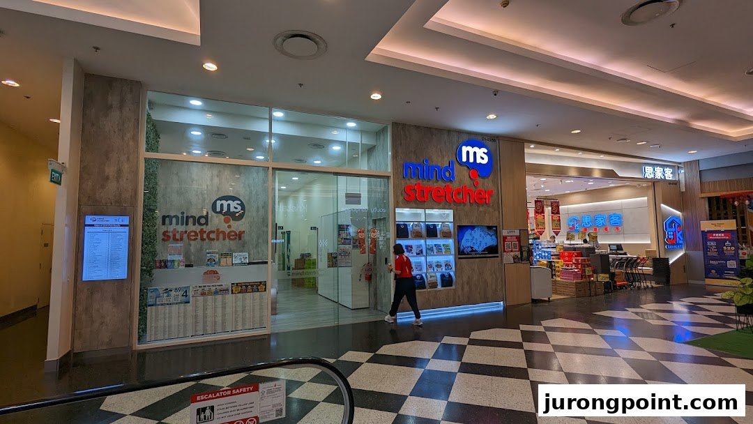 The brightly lit entrance of Mind Stretcher, an education center, within a bustling shopping mall.