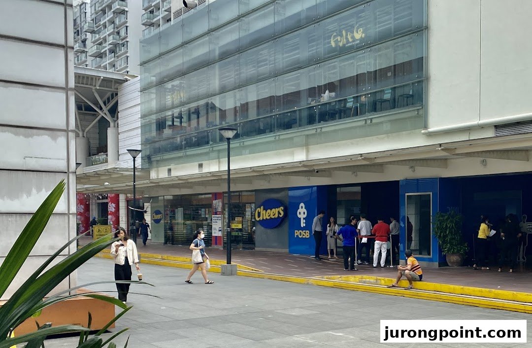 Exterior view of POSB Jurong Point Branch and Cheers convenience store with people queuing outside.