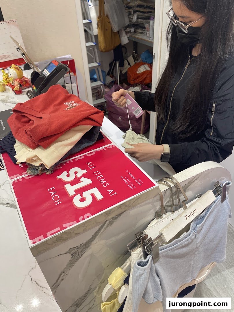 A customer interacts with items at a Purpur clothing store counter during a $15 sale.