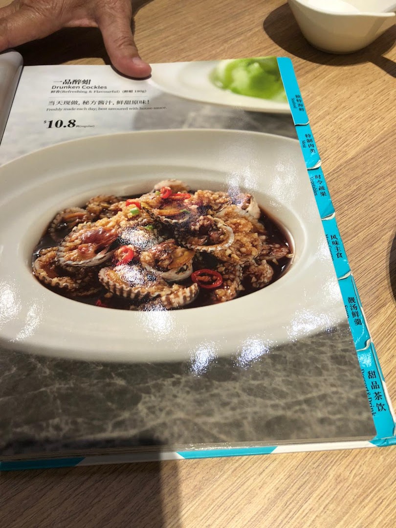 A close-up of a PUTIEN restaurant menu displaying Drunken Cockles with its price and description.