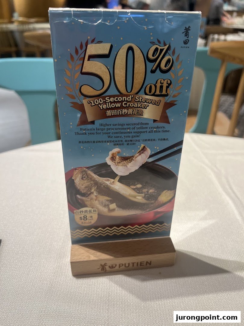 A table-top display at PUTIEN advertising a 50% discount on '100-Second' Stewed Yellow Croaker.