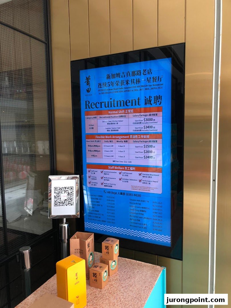 A digital display at PUTIEN showcasing recruitment opportunities and staff welfare benefits, with retail products in the foreground.