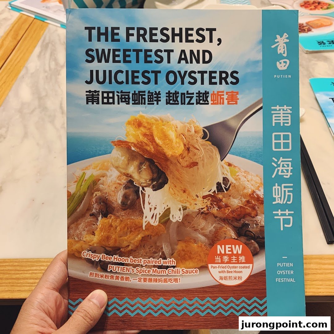 A hand holds a promotional flyer for PUTIEN's Oyster Festival, featuring pan-fried oysters with bee hoon.