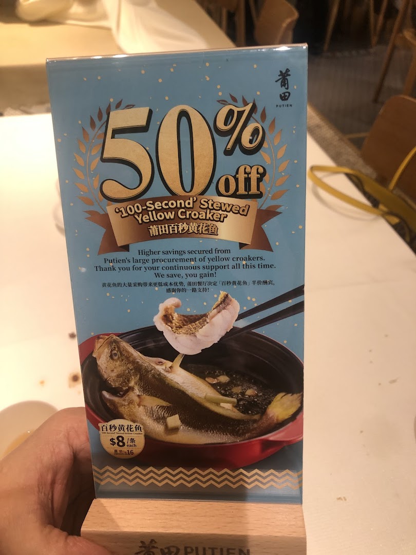 A promotional stand for Putien's '100-Second' Stewed Yellow Croaker, offering 50% off.