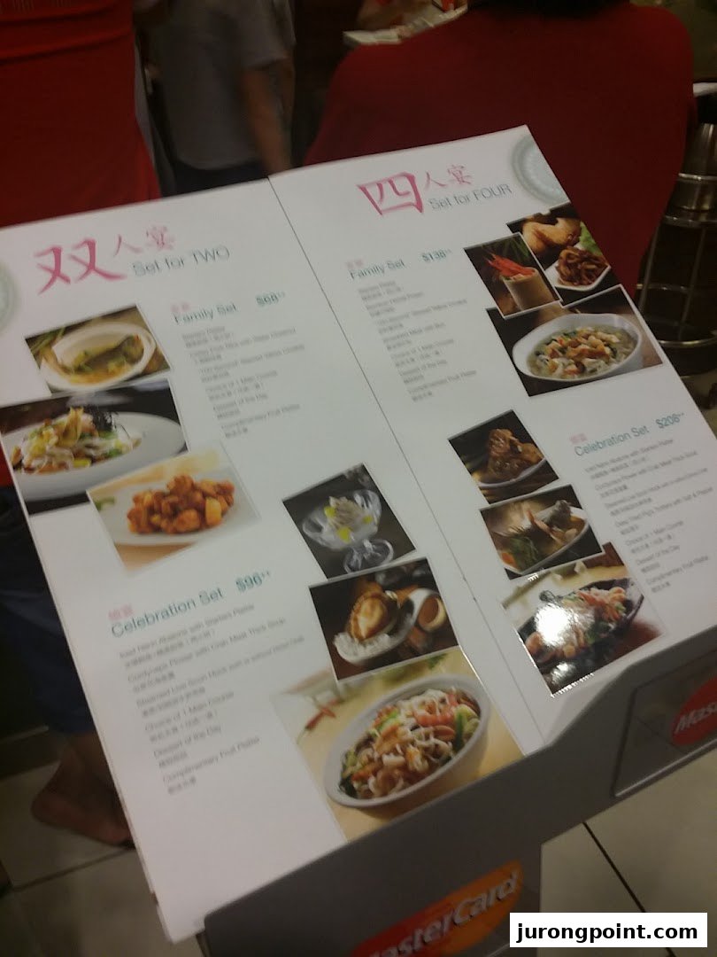 A menu stand displaying set meal options for two and four people with prices and food images.