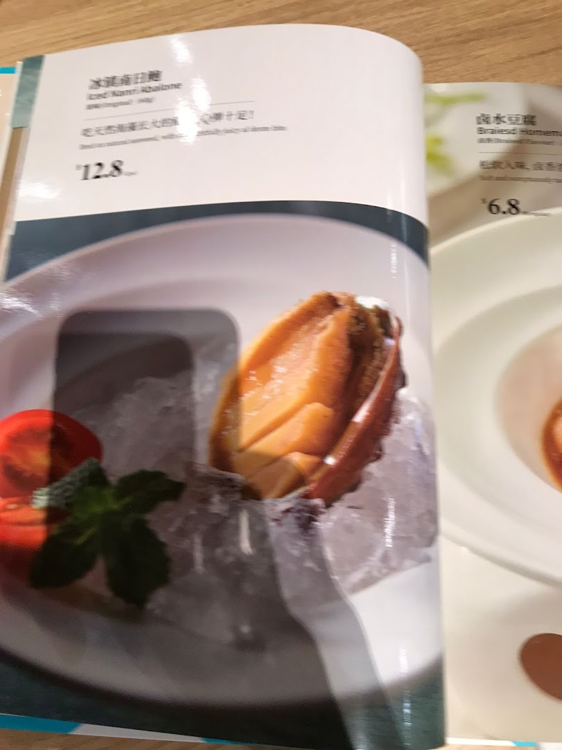 A close-up of a PUTIEN restaurant menu, showcasing Iced Kanni Abalone and Braised Homemade Tofu.