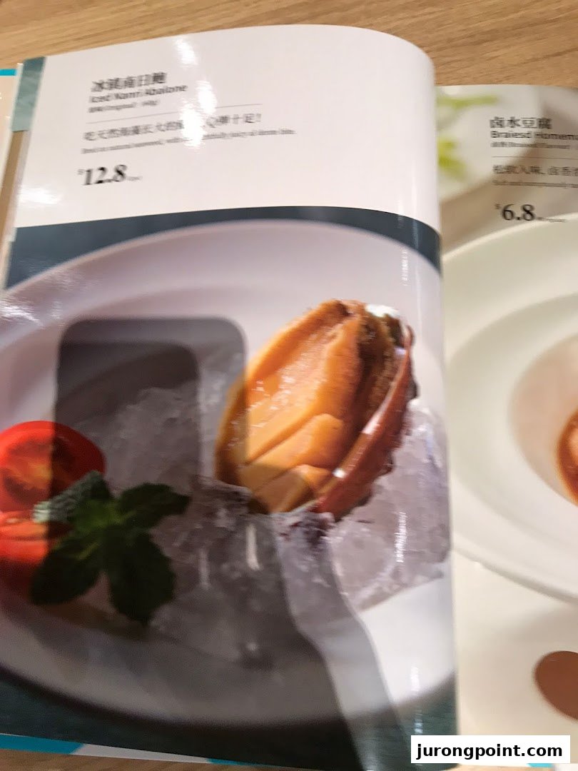 A close-up of a PUTIEN restaurant menu, showcasing Iced Kanni Abalone and Braised Homemade Tofu.