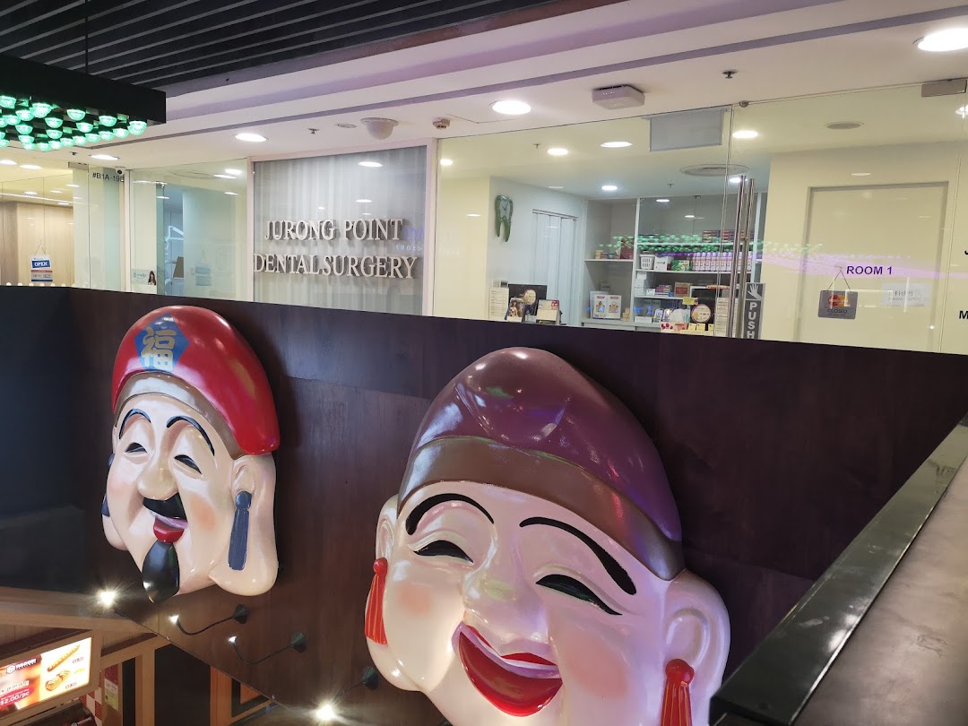 The entrance of Jurong Point Dental Surgery, featuring large decorative masks in the foreground.