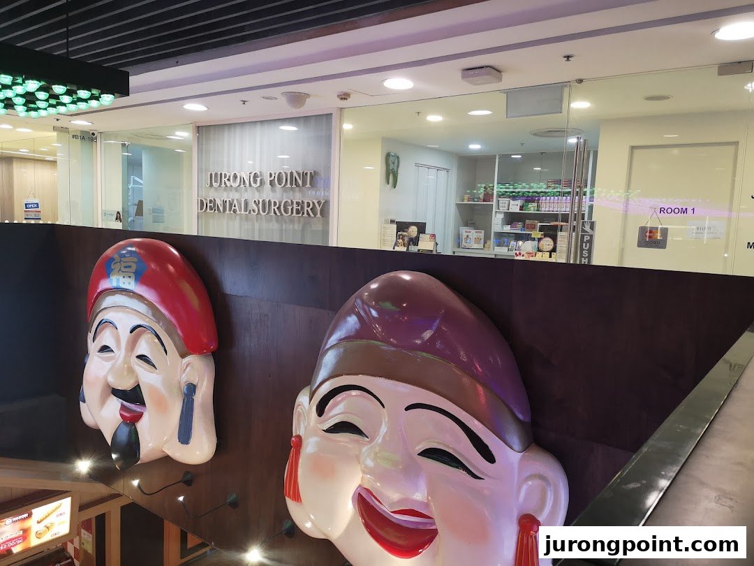 The entrance of Jurong Point Dental Surgery, featuring large decorative masks in the foreground.