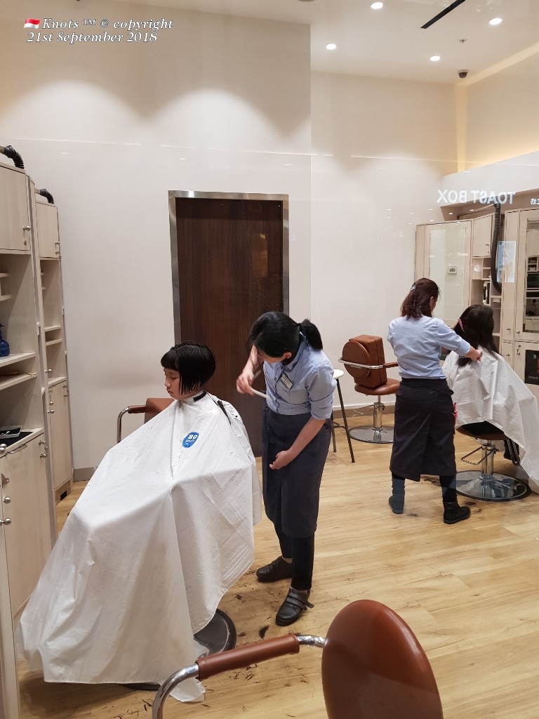 Customers receive efficient haircuts from stylists inside QB House.